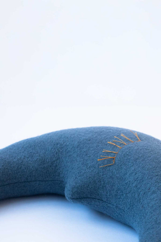 Detail des kleinen Mondkissens in Taubenblau mit liebevollen Wimpern in Gelb für Babys und Kinder
