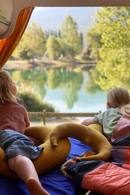 Kinder kuscheln im Camper mit großem und kleinen Mondkissen in Goldgelb mit Blick ins Grüne