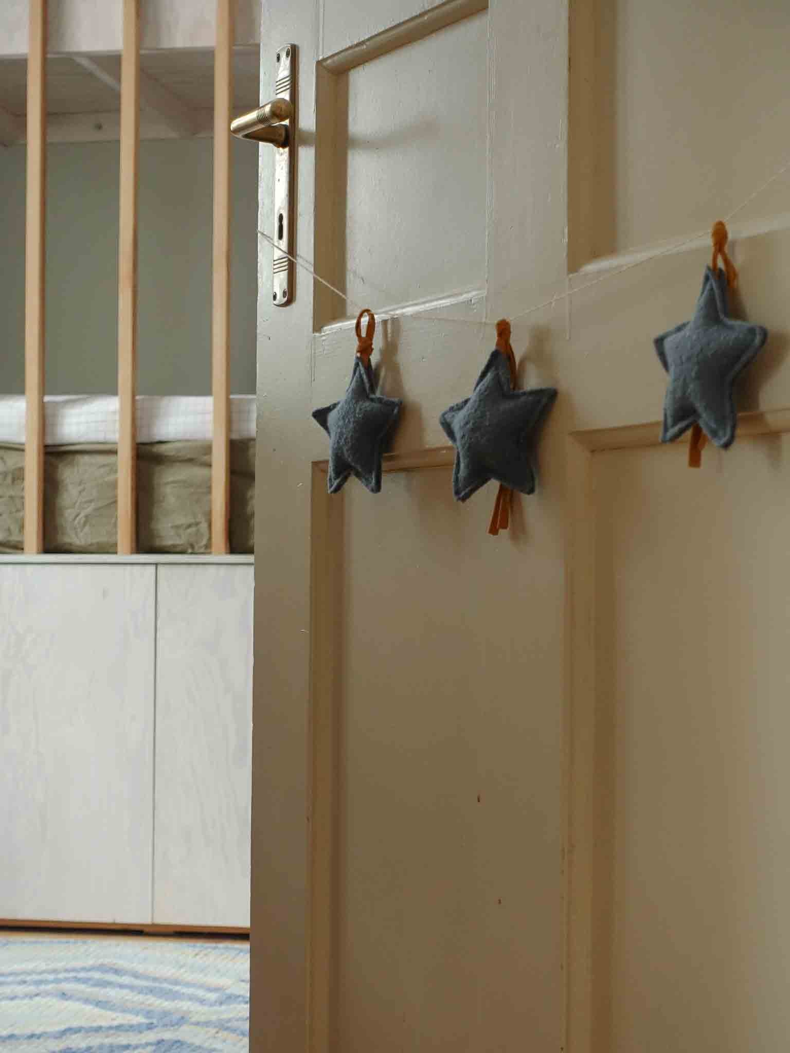 Sternengirlande in blau mit drei Sternenkissen an Kinderzimmertür arrangiert