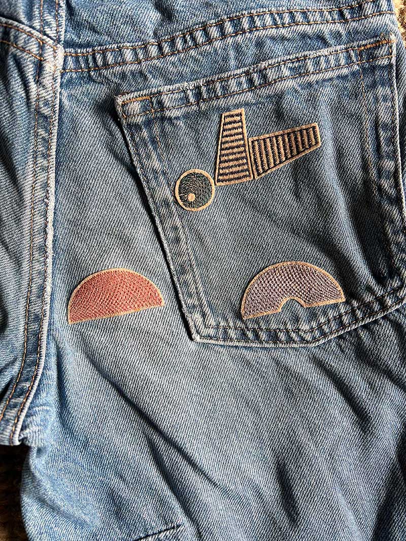 Abstrakte Szene mit Vogel aus modularen geometrischen Bügelpatch-Elementen auf Jeans als Anwendungsbeispiel