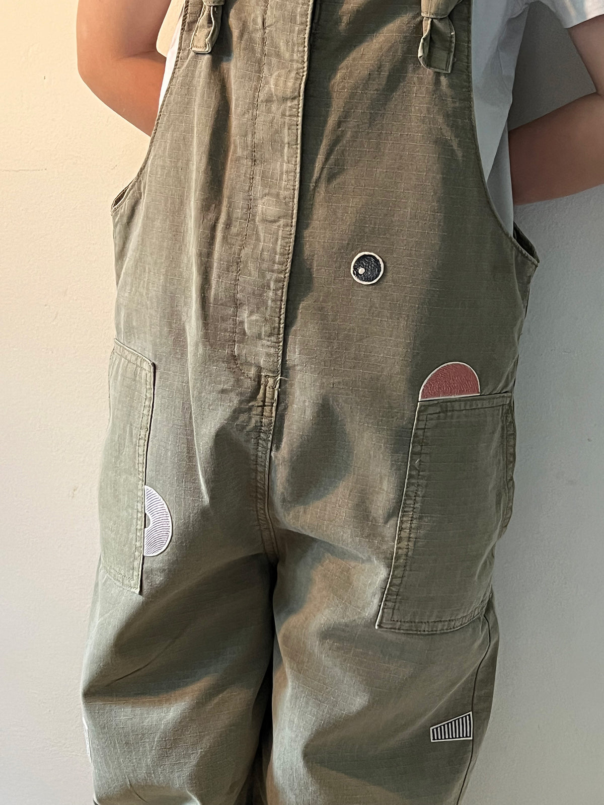 Kind trägt ein Latzhose mit einem Bügelpatch-Set aus 5 geometrischen Teilen arrangiert zu grafischem Muster