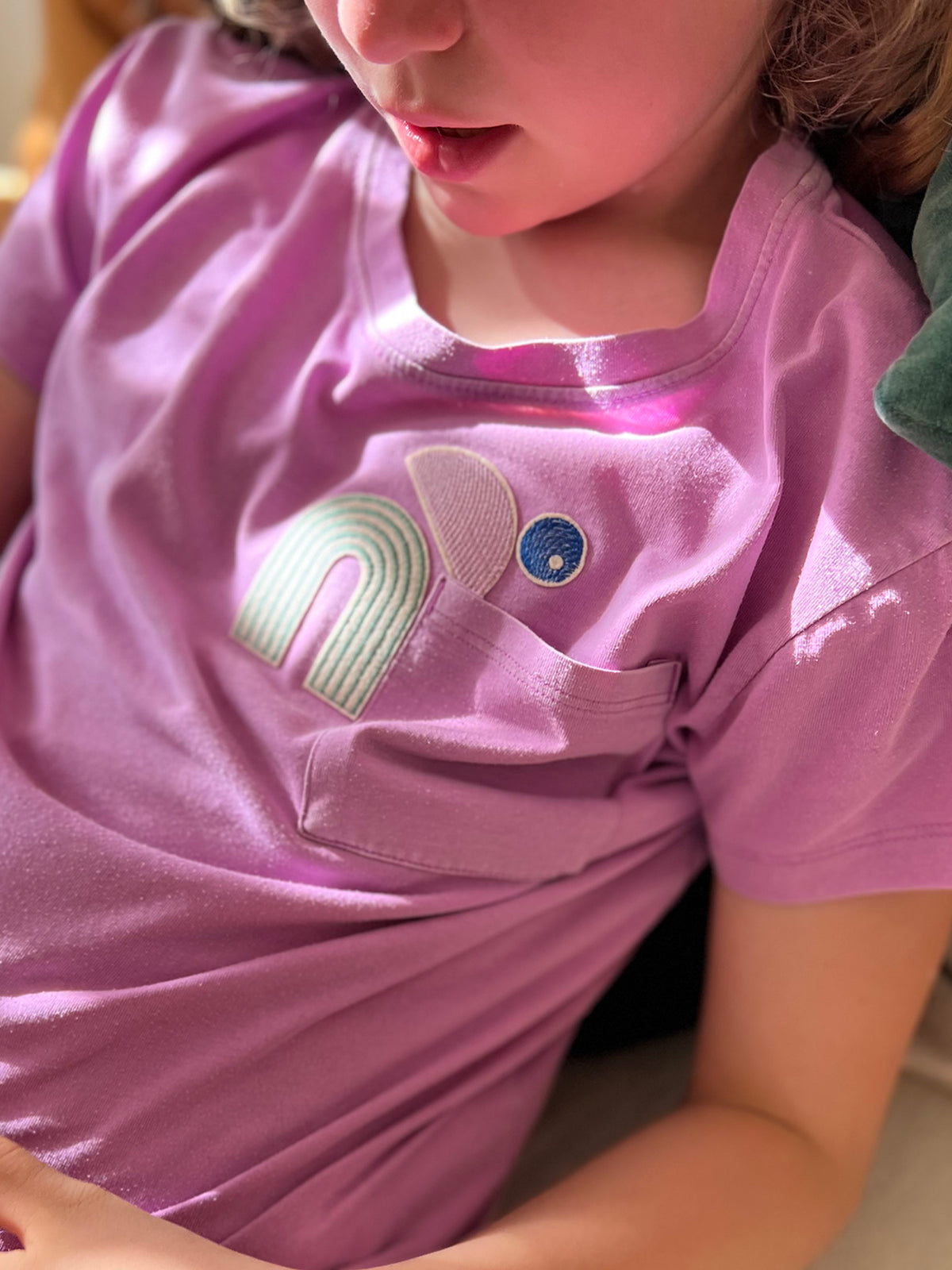 Kind trägt ein T-Shirt mit einem Bügelpatch-Set aus 3 Teilen arrangiert zu einer gebeugten Figur, die in eine T-Shirttasche hineinschaut