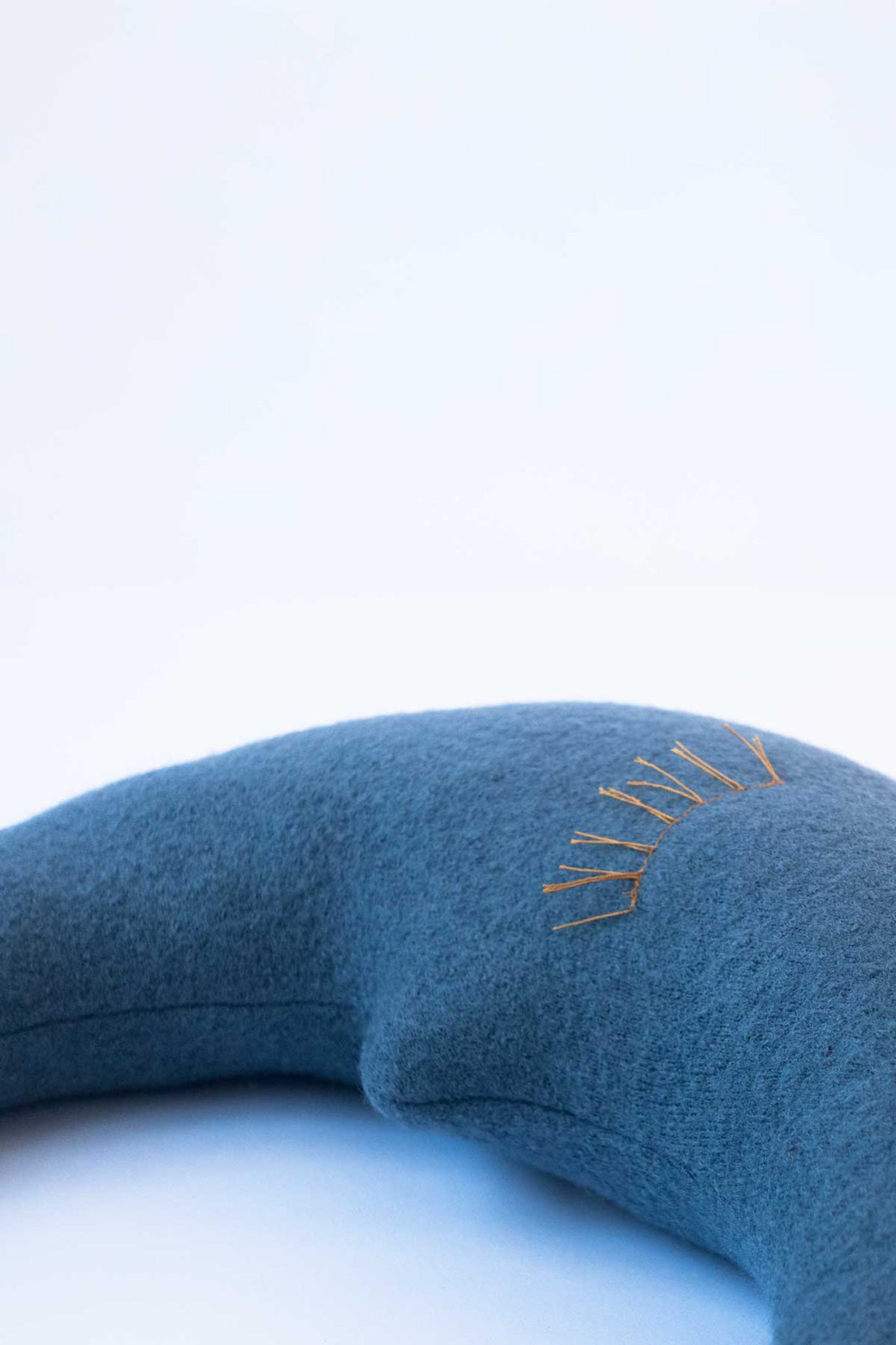 Detail des kleinen Mondkissens in Taubenblau mit liebevollen Wimpern in Gelb für Babys und Kinder